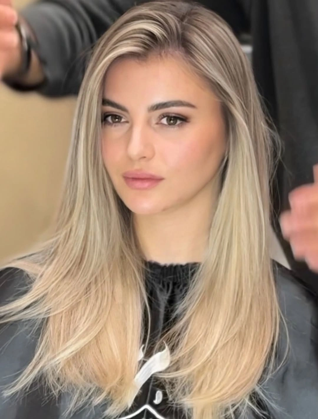 Long layered blonde hair with root shadow and pale front lengths
