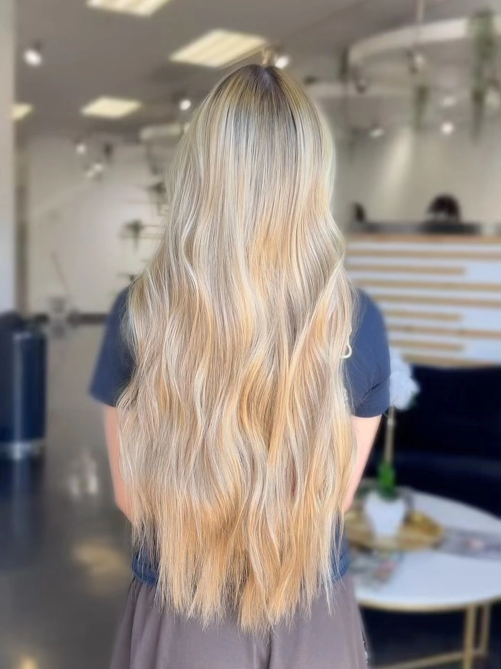 Very long creamy blonde waves with darker roots and warm lengths