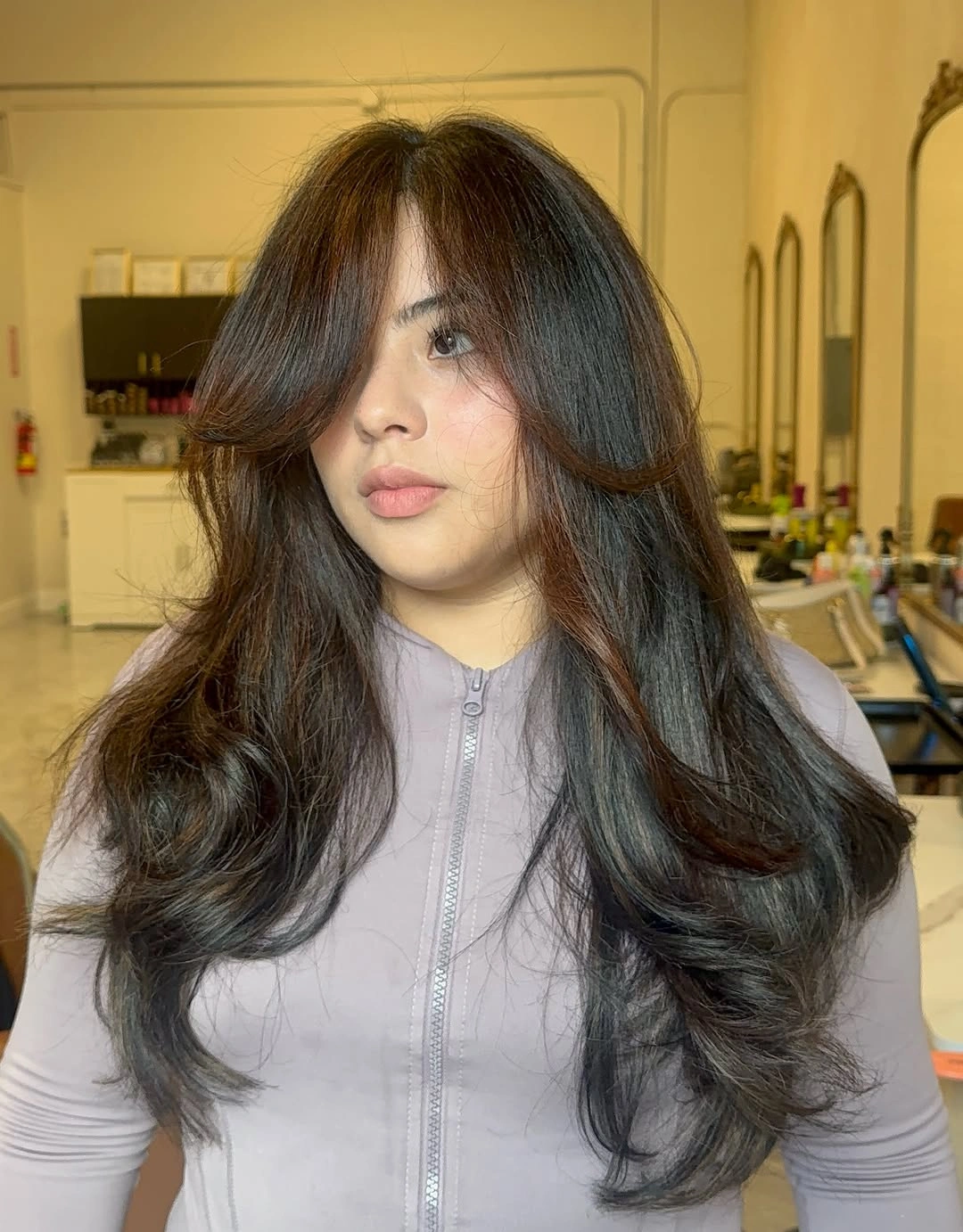 Layered dark brunette hair with curtain bangs and warm ribbons