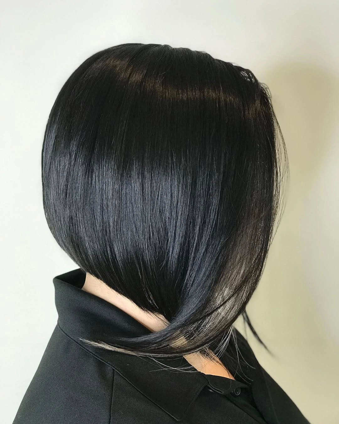 Glossy black angled bob with tucked bevel and sweeping front edge