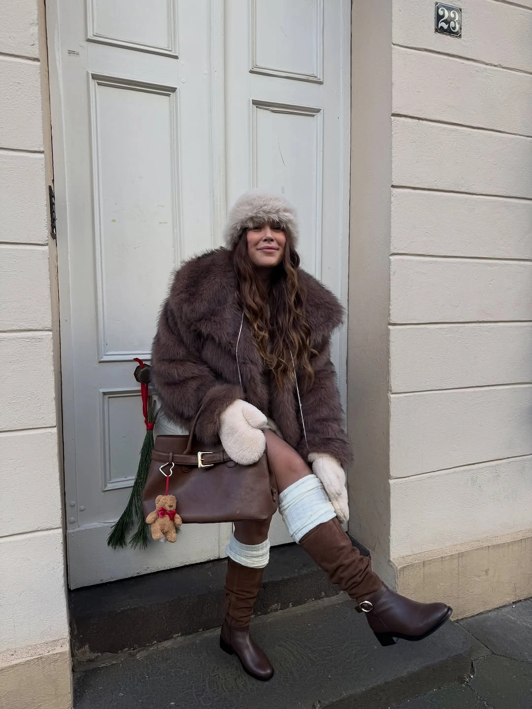 Brown textured coat with white lower layer, tall boots, and burgundy bag
