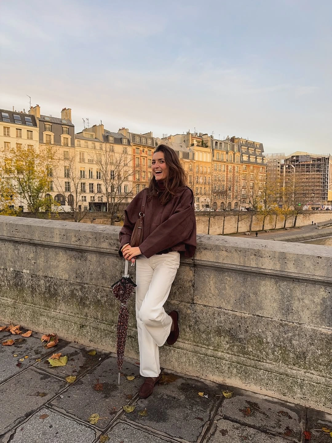 Deep brown draped knit with loose cream trousers, boots, and brown bag