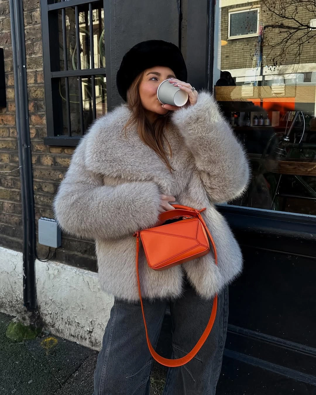 Cream textured jacket, blue jeans, black boots, and bright orange bag