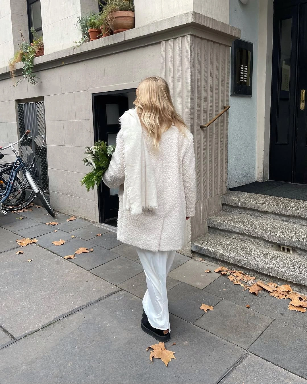 Oversized cream textured coat with white trousers, pale scarf, and black ankle boots