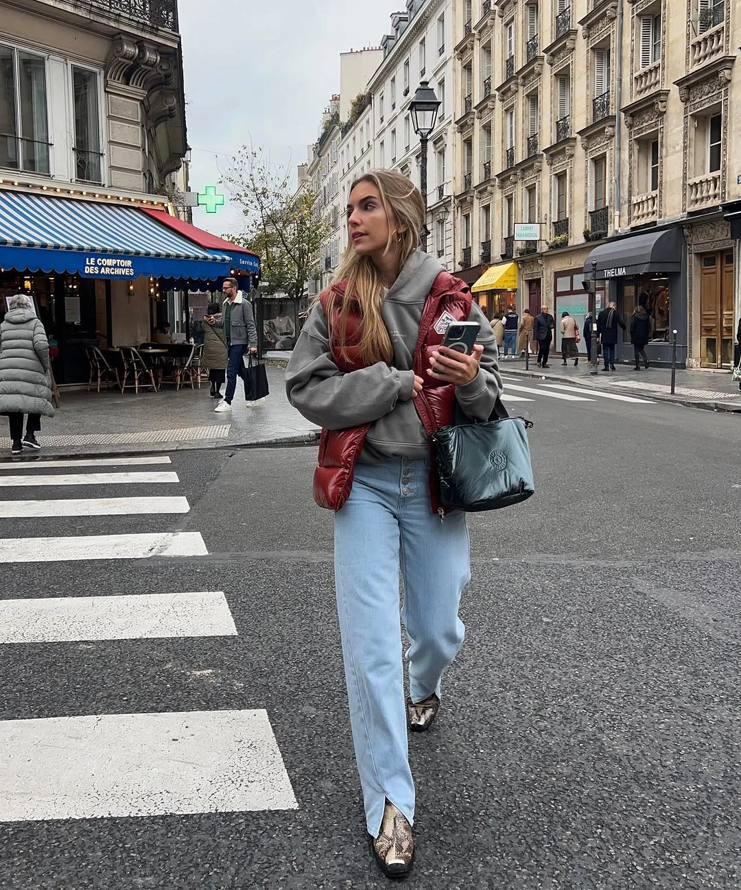 Burgundy puffer vest over gray knit with light blue jeans and gray bag