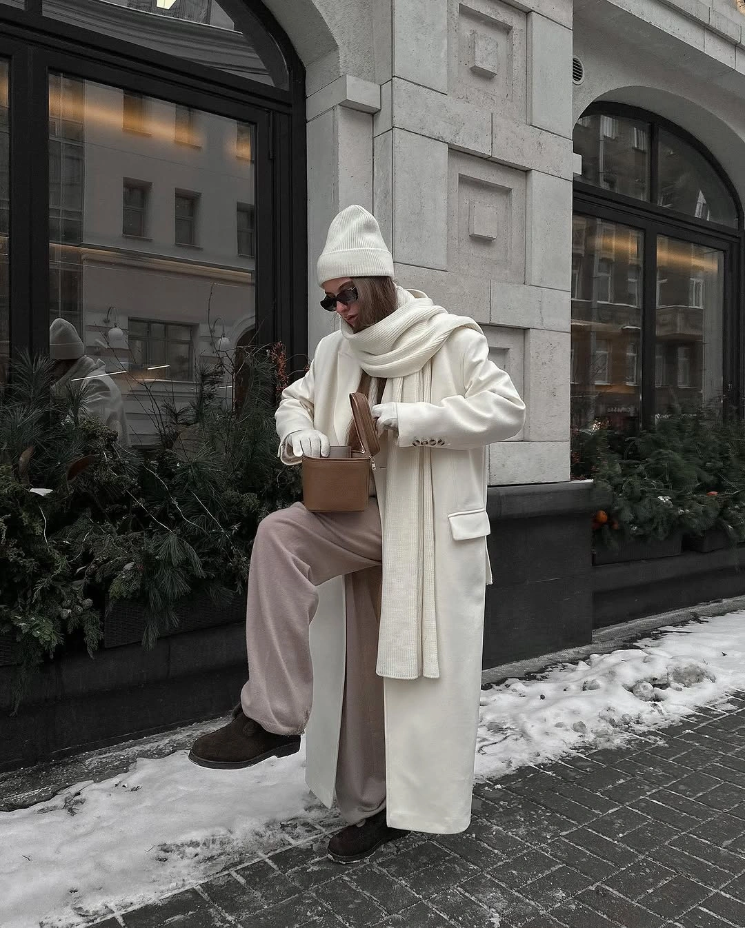 Ivory coat, scarf, beanie, wide trousers, dark boots, and brown tote