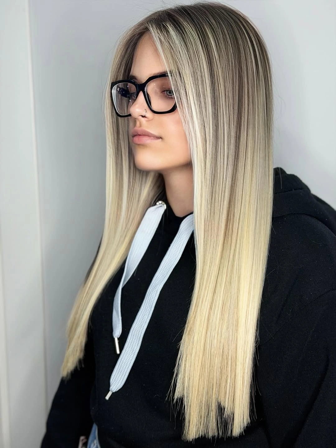 Long straight blonde with dark roots and black glasses