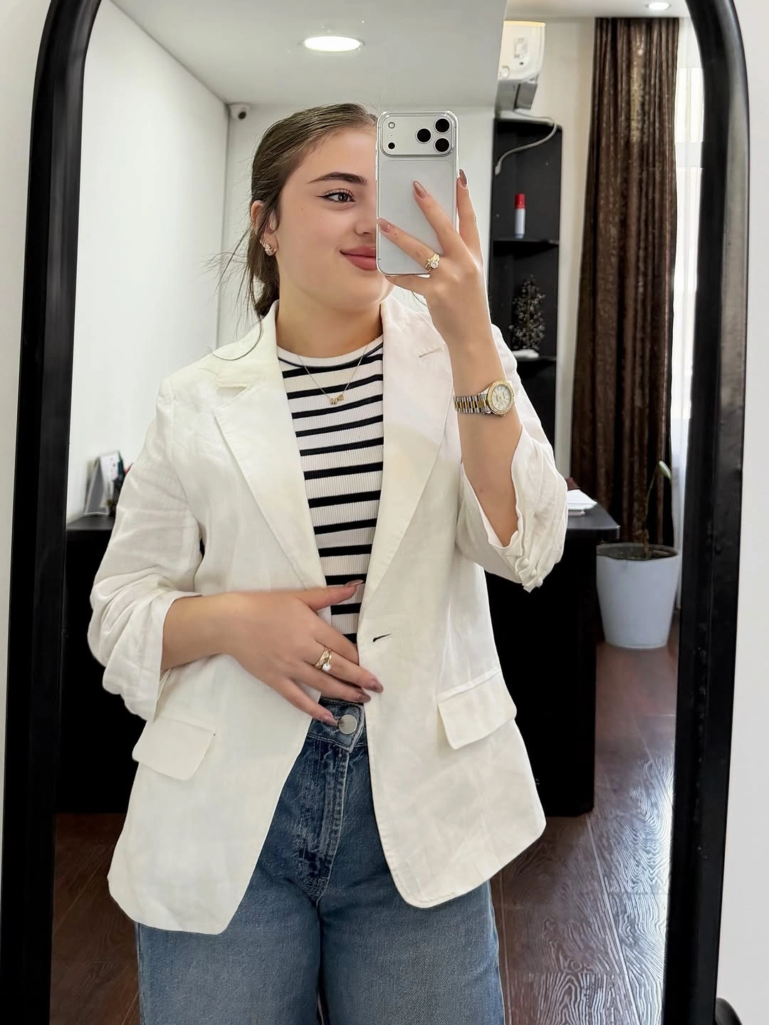 Ivory blazer over a black-and-white striped top and blue jeans, with pushed-up sleeves and a watch.