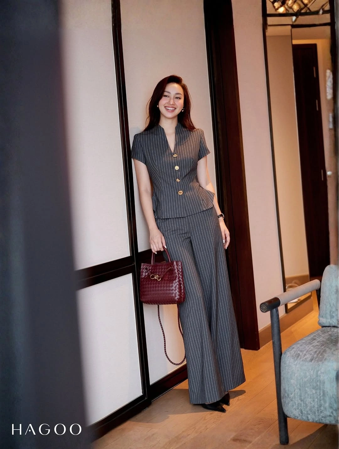 Gray pinstriped short-sleeve top and matching wide-leg trousers with a burgundy handbag.