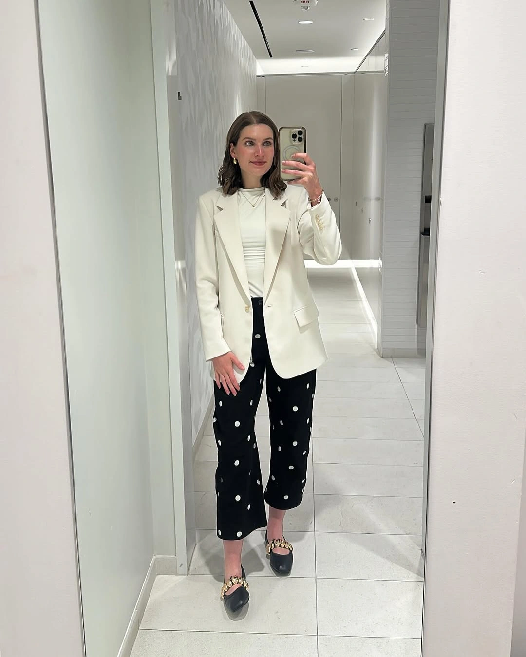 Long ivory blazer over a pale top and cropped black trousers with white motifs.