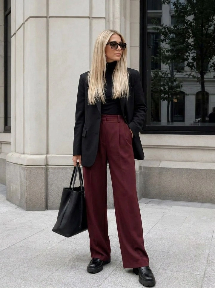 Black blazer and high-neck top with burgundy wide-leg trousers, black shoes, and tote.
