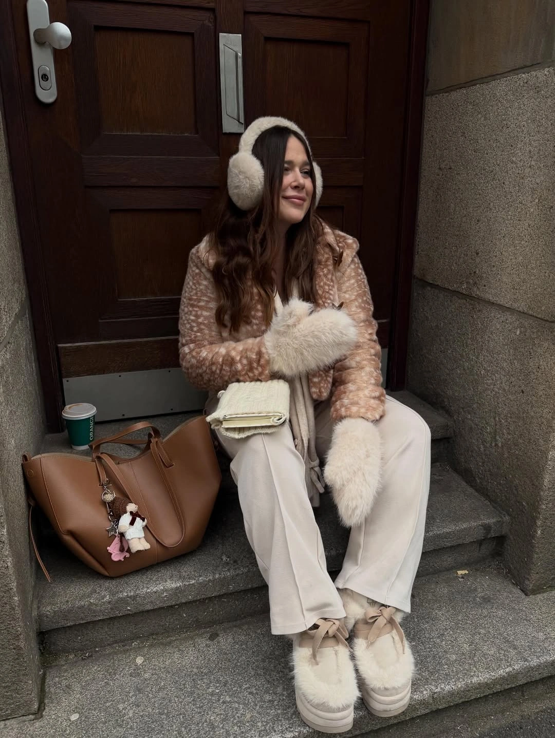 Brown patterned jacket with cream earmuffs, trousers, and brown tote