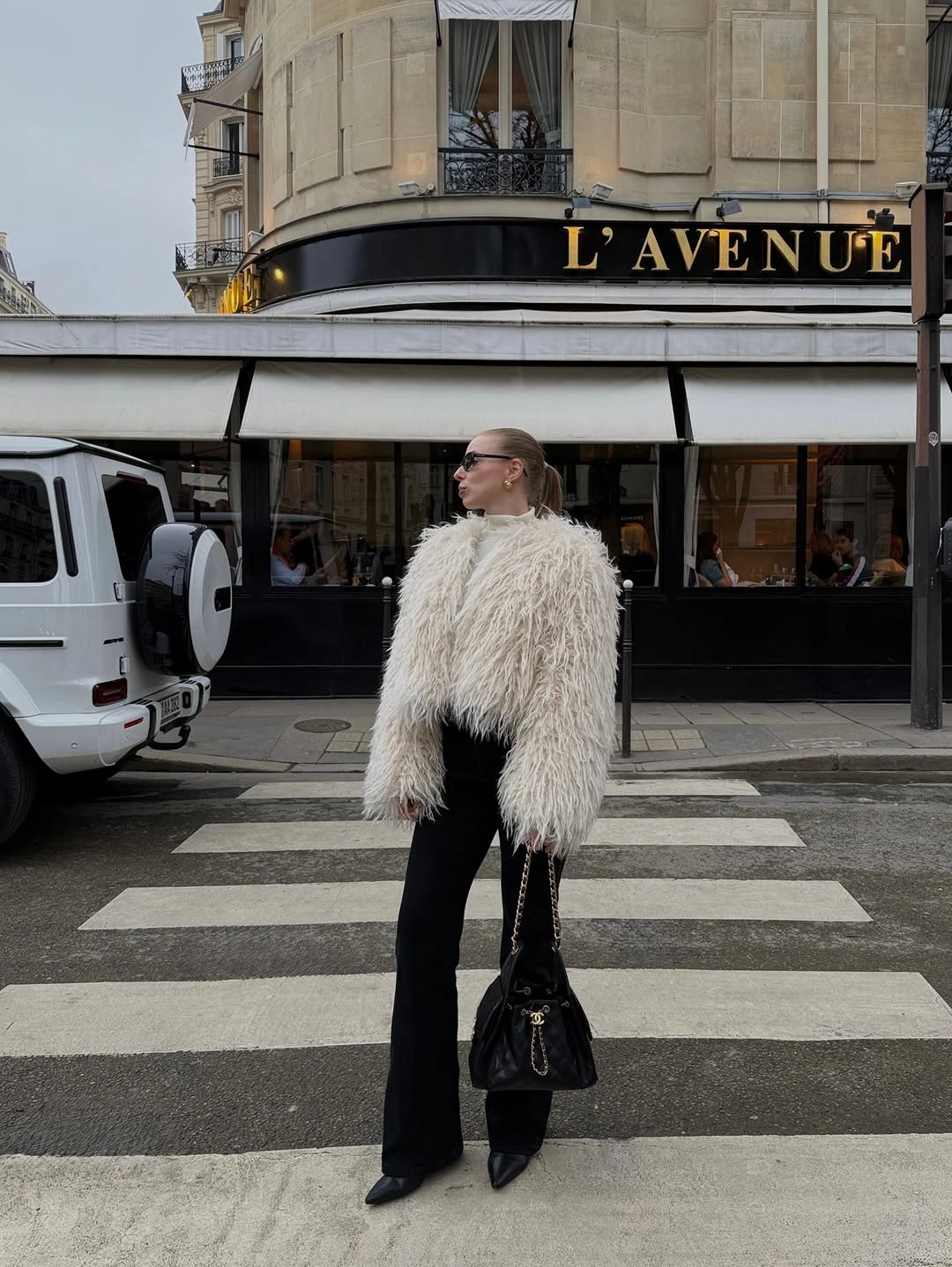 Cream shaggy-textured outer layer with black flared trousers and pointed boots