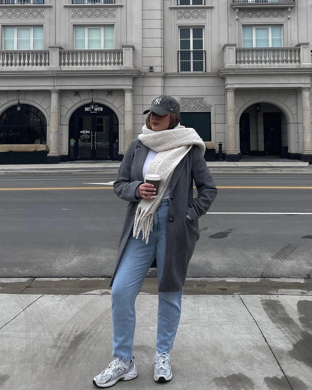 Gray long coat with a white scarf, jeans, cap, and sneakers