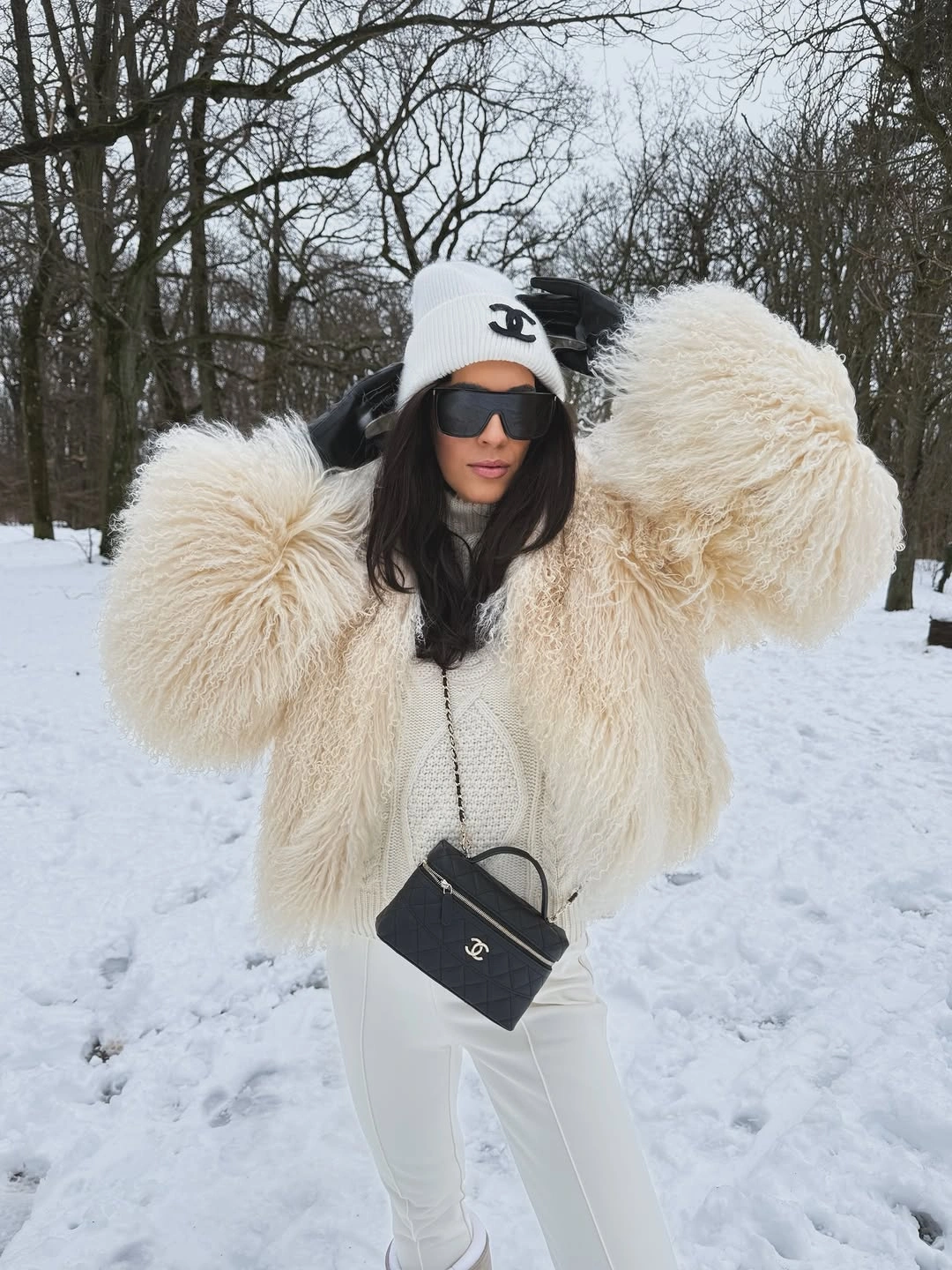 Cream textured coat with white layers, white pants, and a black bag