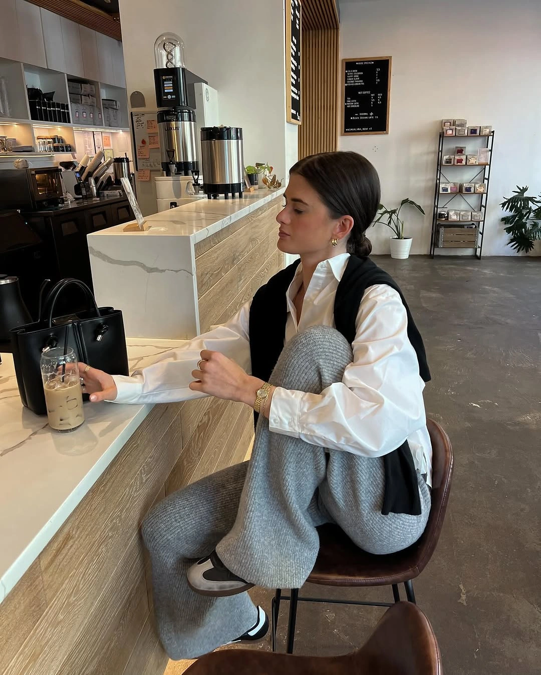 White shirt, black vest, wide gray trousers, sneakers, and black tote