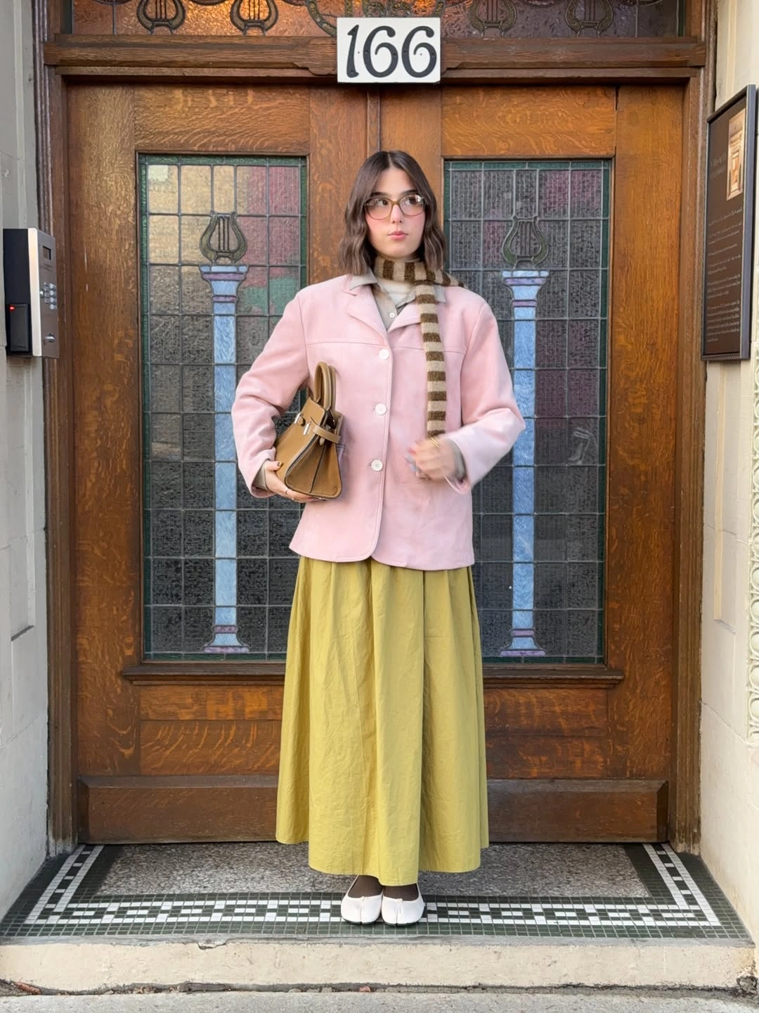 Pink short coat, striped scarf, yellow-green skirt, and white shoes