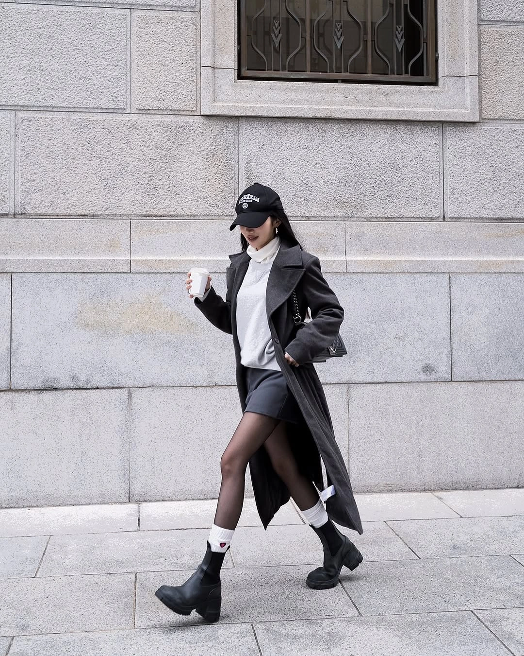 Charcoal coat, white top, black shorts, sheer tights, and ankle boots