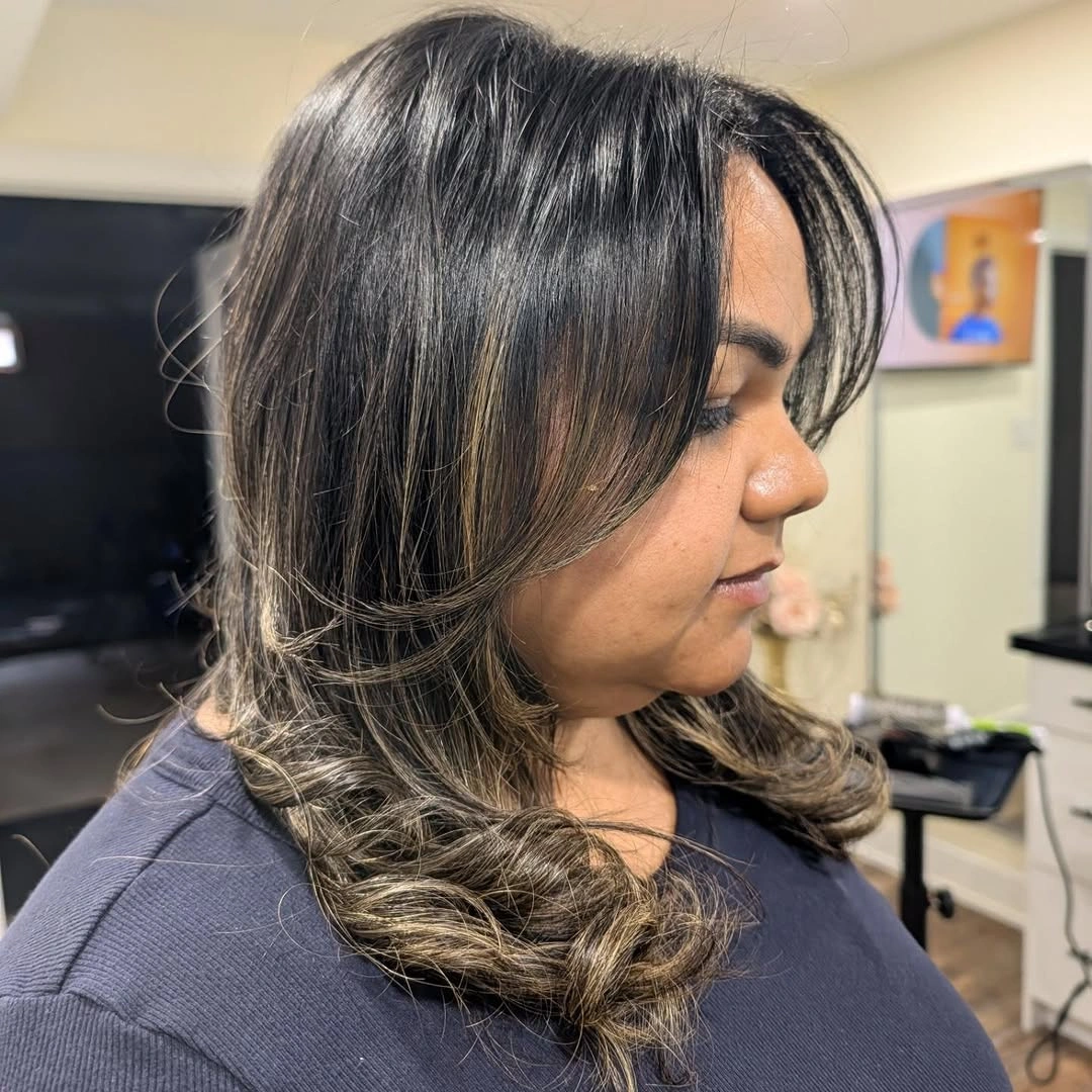 Medium-length dark hair with lighter strands and layered curled ends