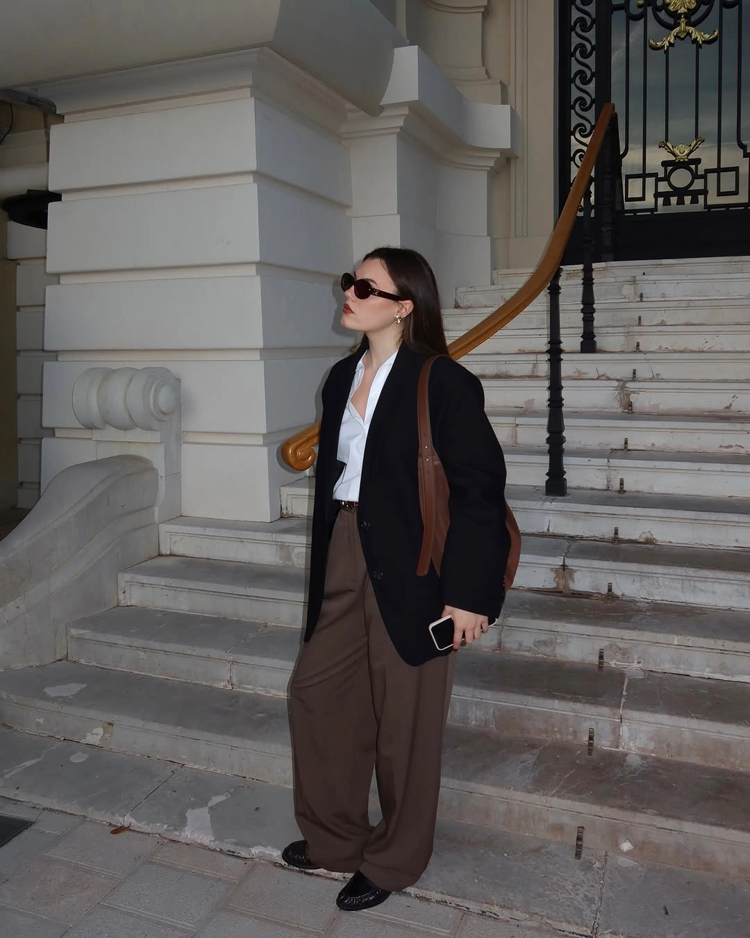 Black outer layer, white blouse, brown wide-leg trousers, and black flats