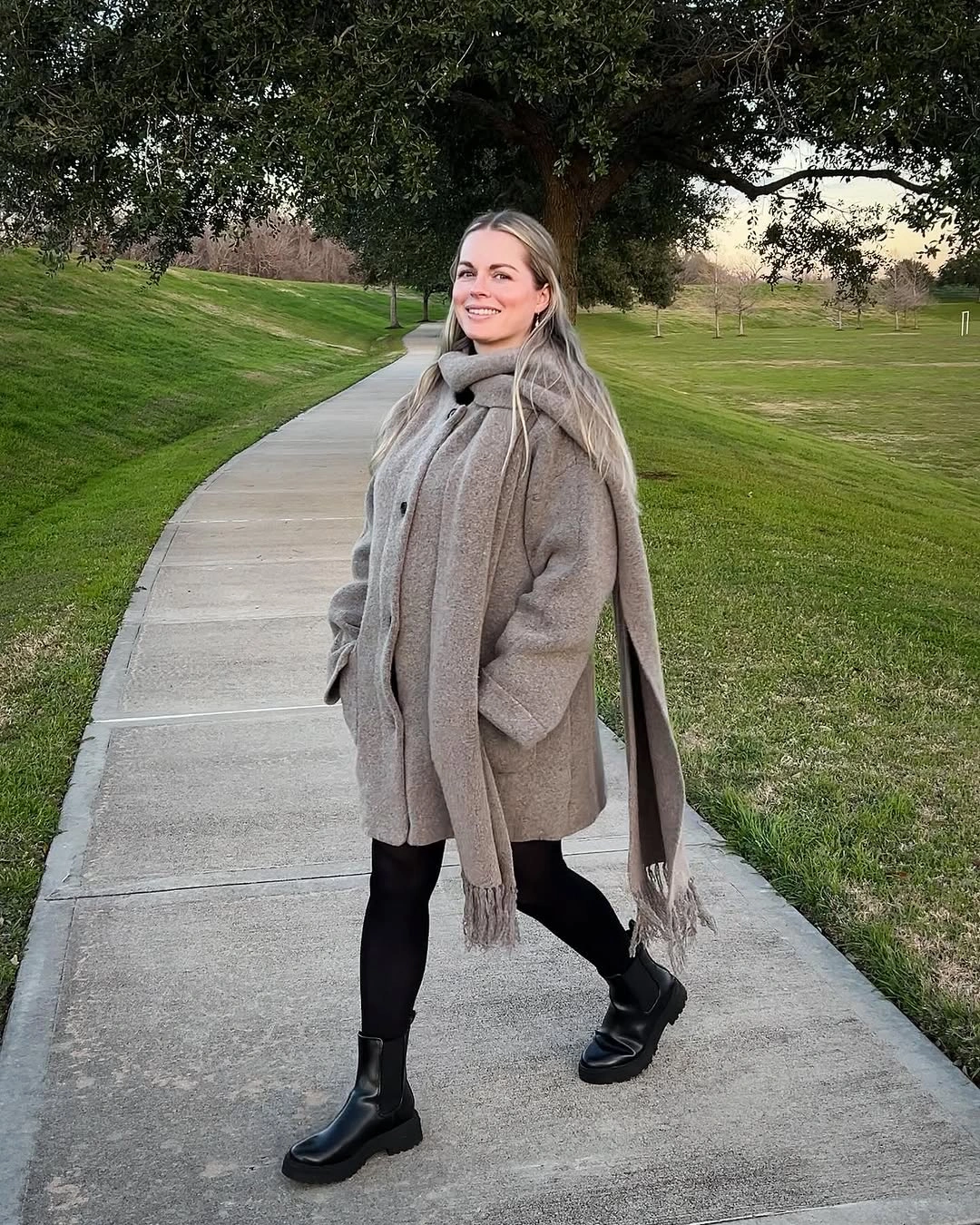 Taupe coat and long scarf with black tights and ankle boots