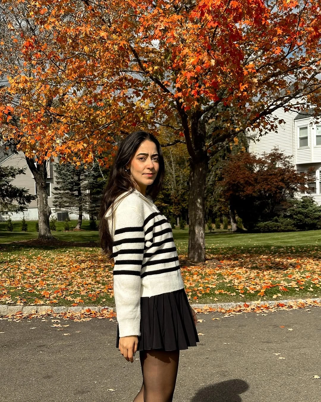Black-and-white striped sweater, black pleated skirt, tights, and dark shoes