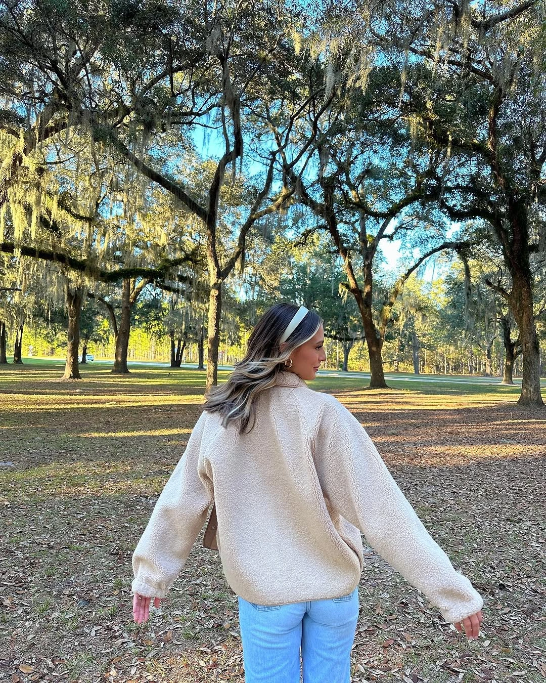 Cream textured-looking pullover with light blue jeans shown from behind