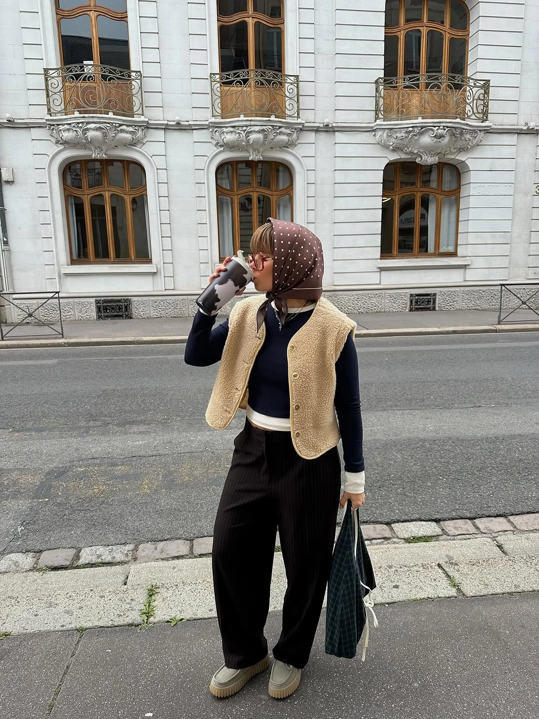 Cream textured-looking vest over dark top and black trousers with patterned headscarf