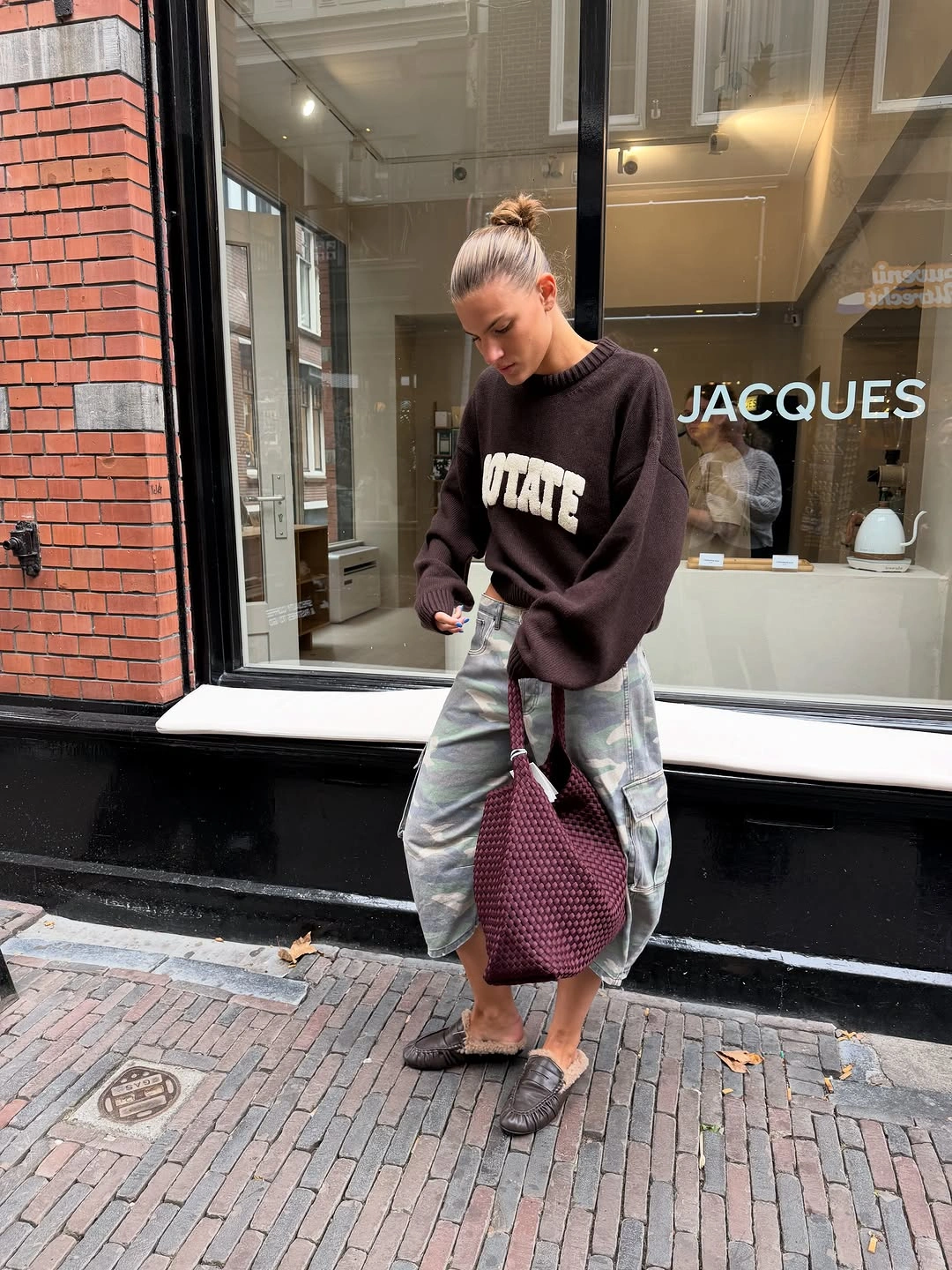 Dark brown oversized sweater, loose patterned lower garment, burgundy bag, and black flats