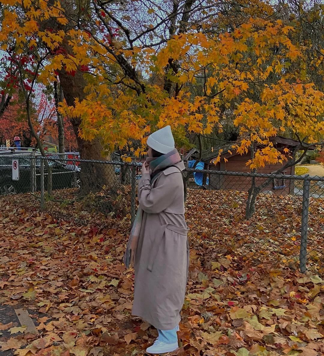 Long taupe coat, layered scarf, white cap, and pale blue boots