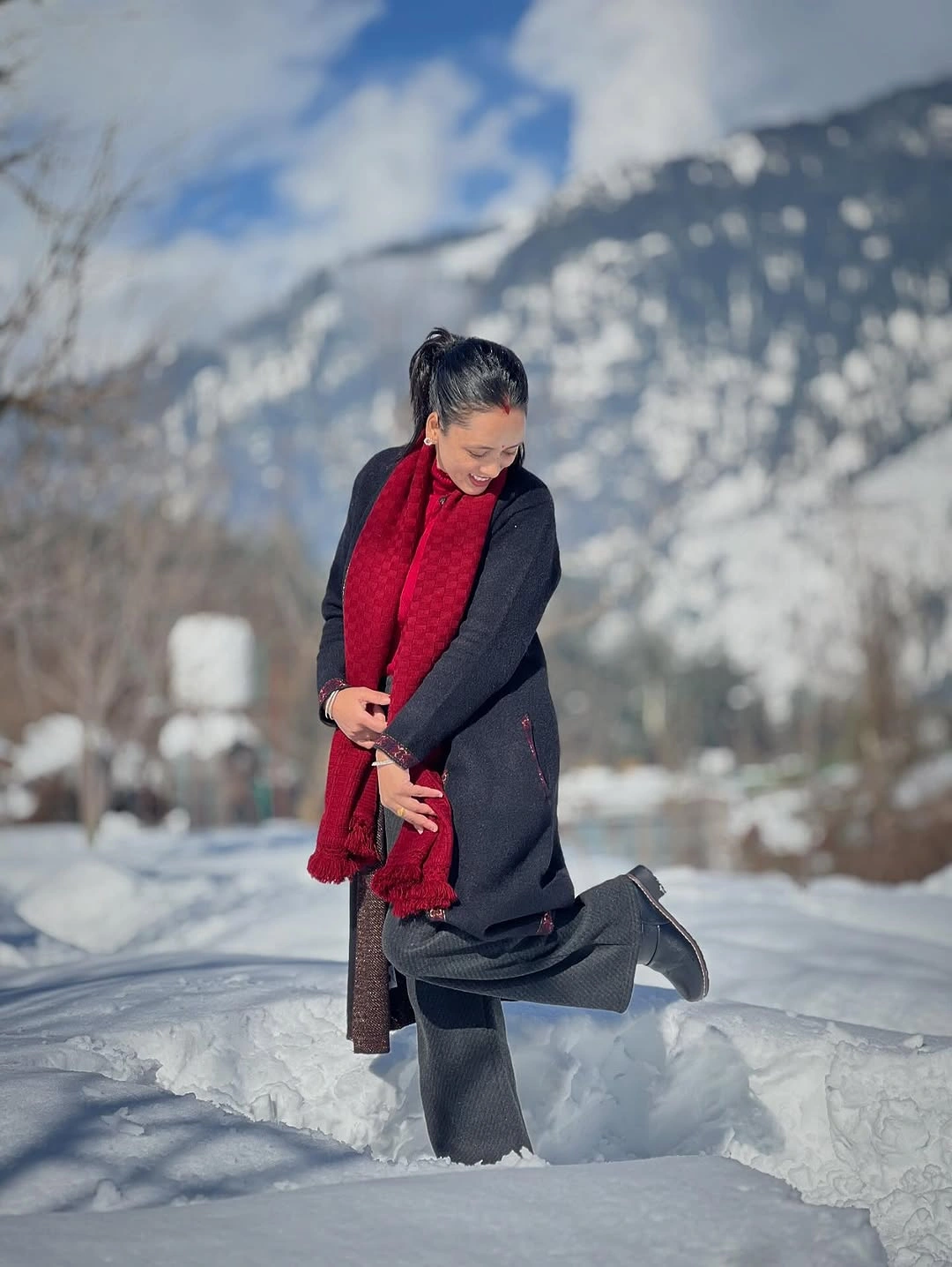 Dark coat, gray lower layer, red scarf, and dark boots