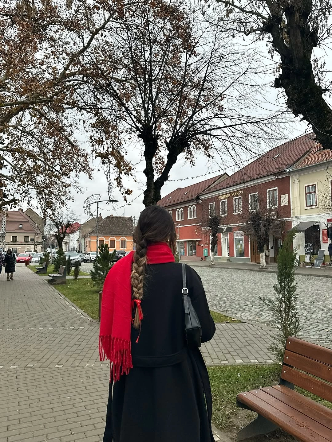 Dark back-view outfit with vivid red scarf and black shoulder bag