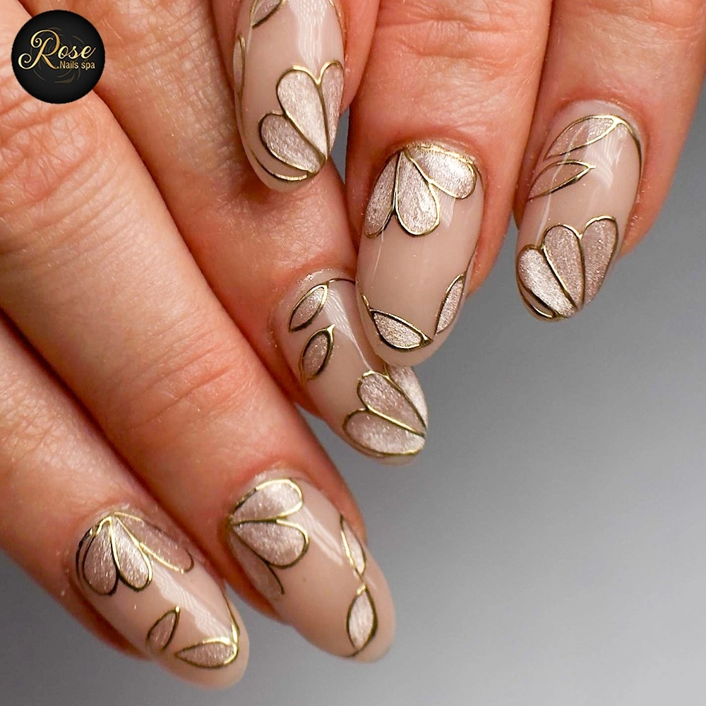 Nude almond nails with gold-colored outlines and cream petal shapes