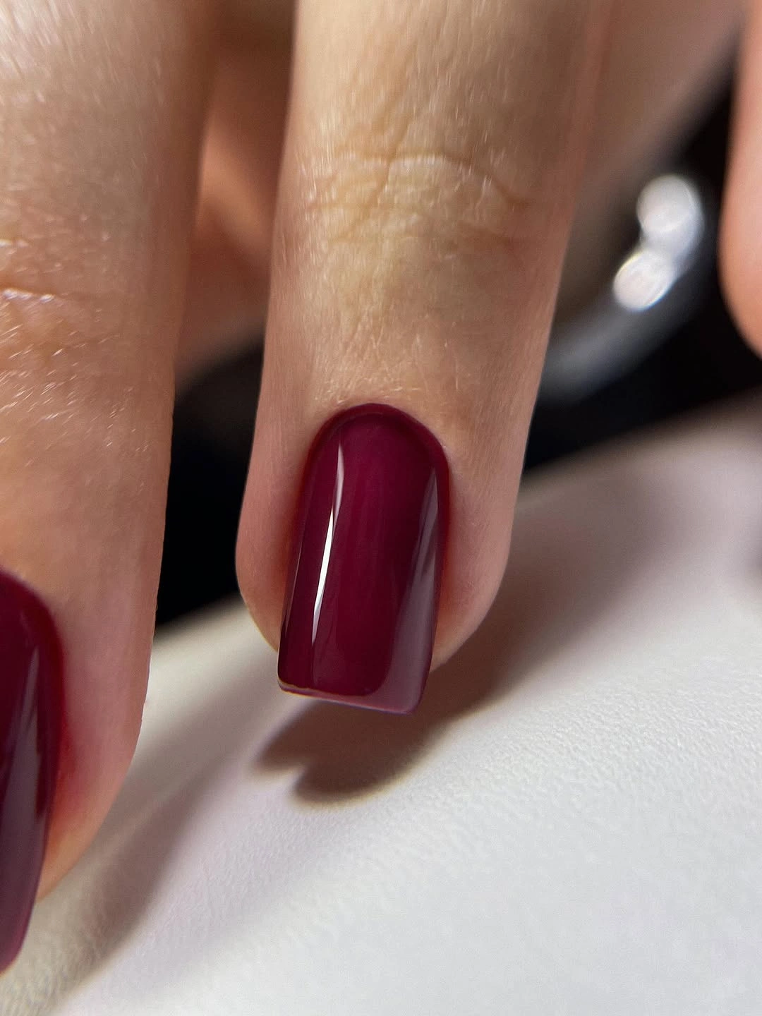 Glossy burgundy rounded-square nails with smooth dark red polish