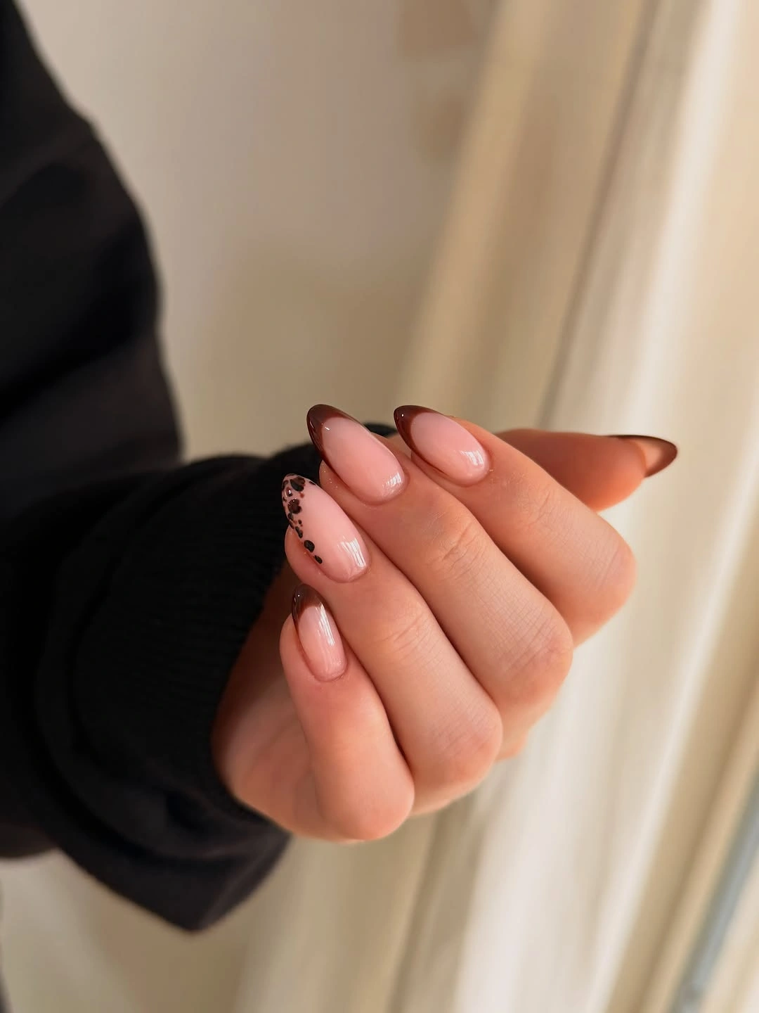 Almond nails with brown French tips and leopard-like side accent