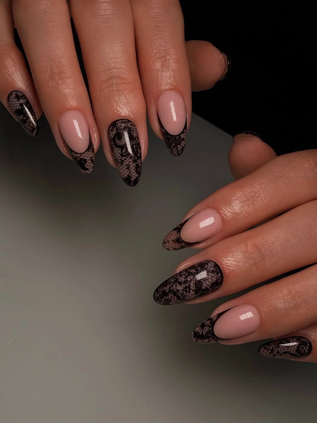 Nude almond nails with black lace-like patterned tips