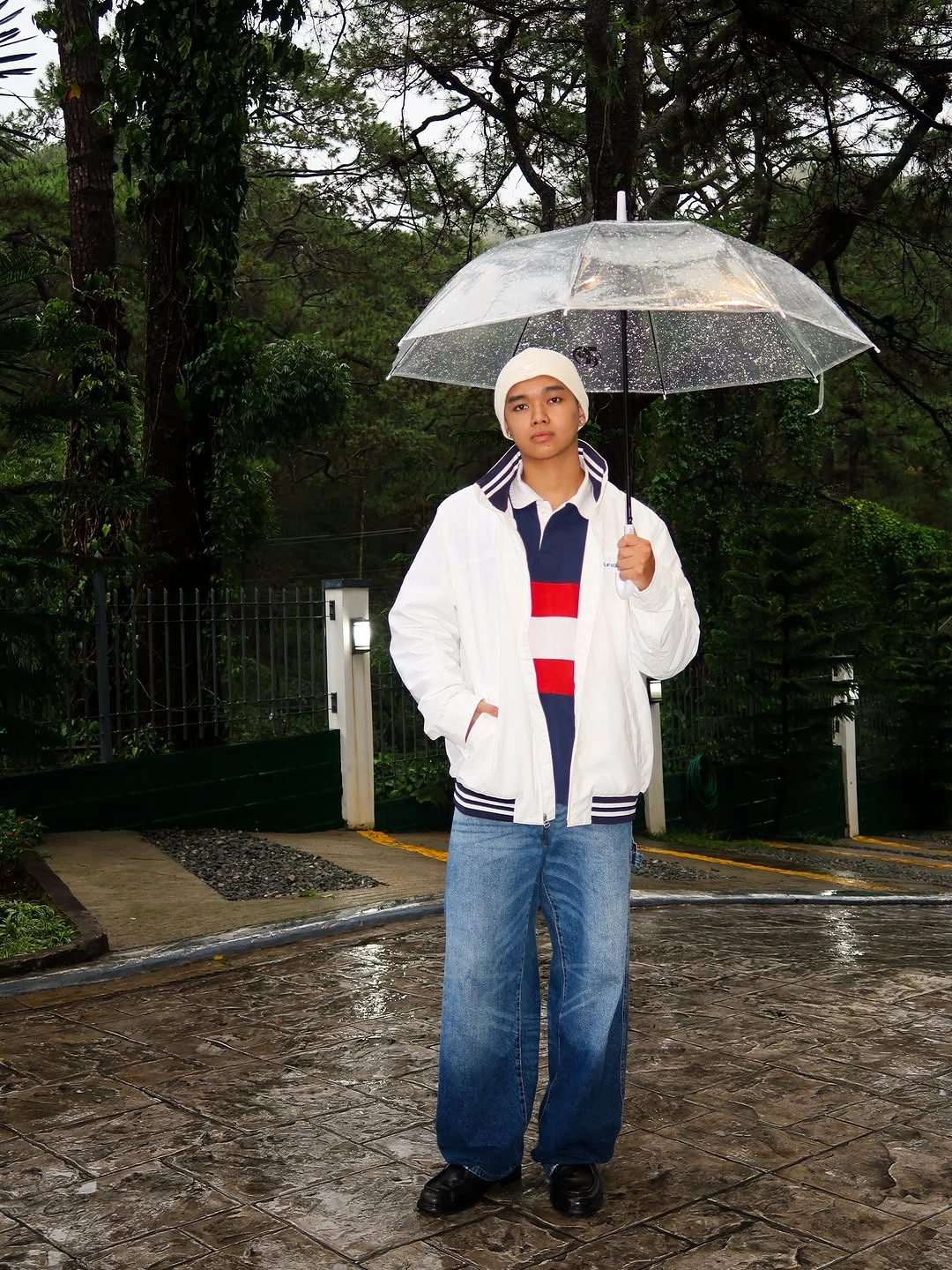 White jacket with navy and red trim, blue jeans, and umbrella