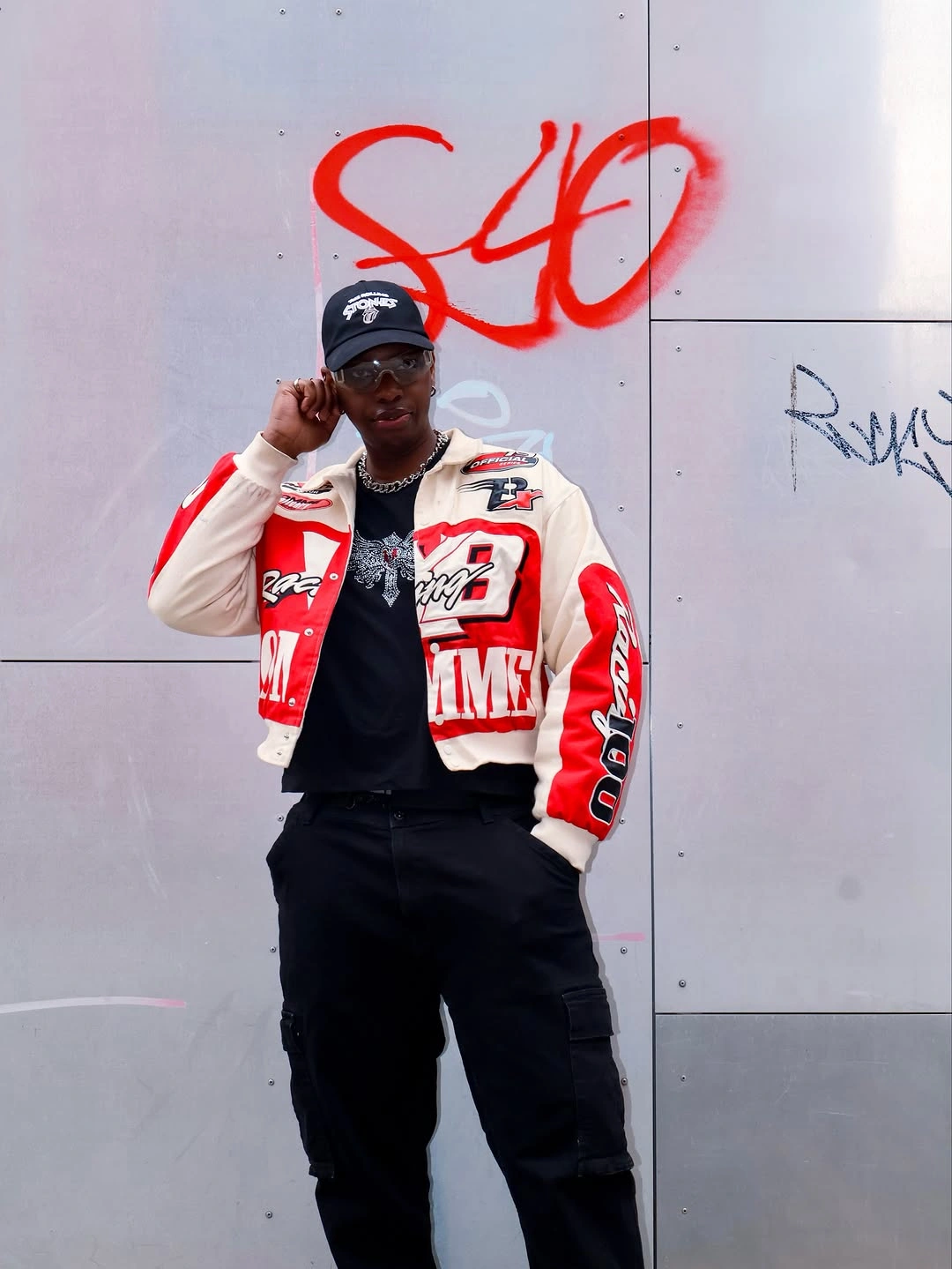 Red and white graphic jacket with black trousers and dark cap