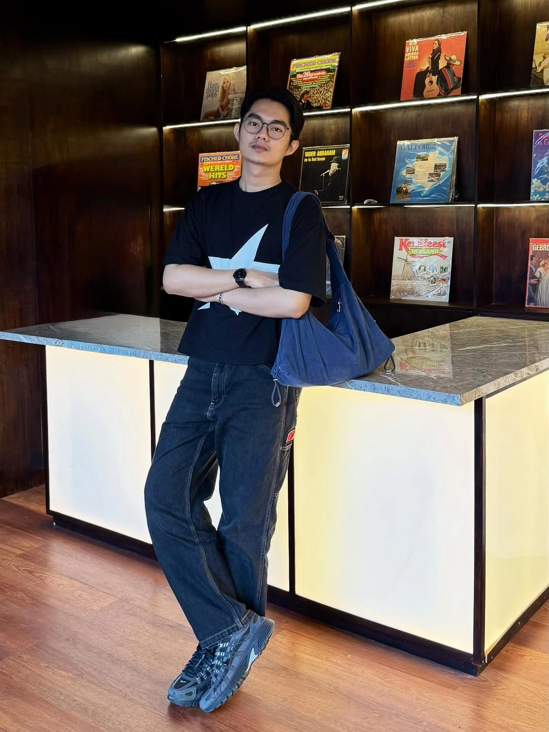 Black T-shirt, navy wide trousers, and cobalt shoulder bag