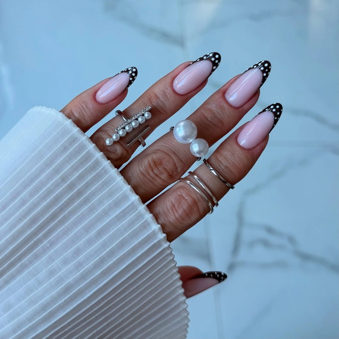 Long soft pink almond nails with black dotted French tips and white dots