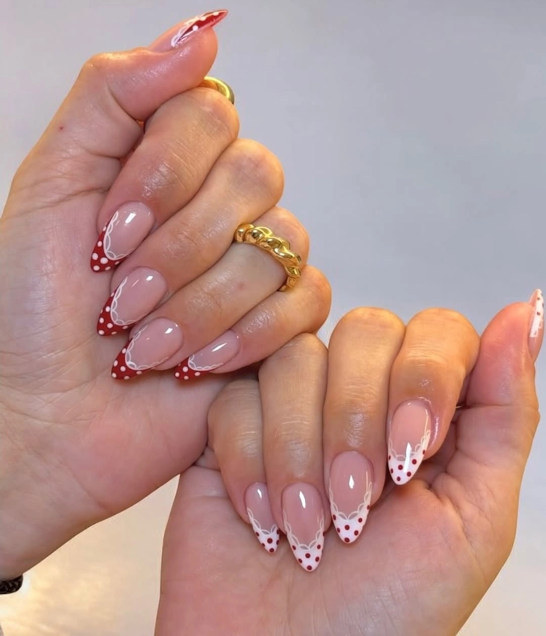 Medium blush pink almond nails with curved berry red dotted French tips