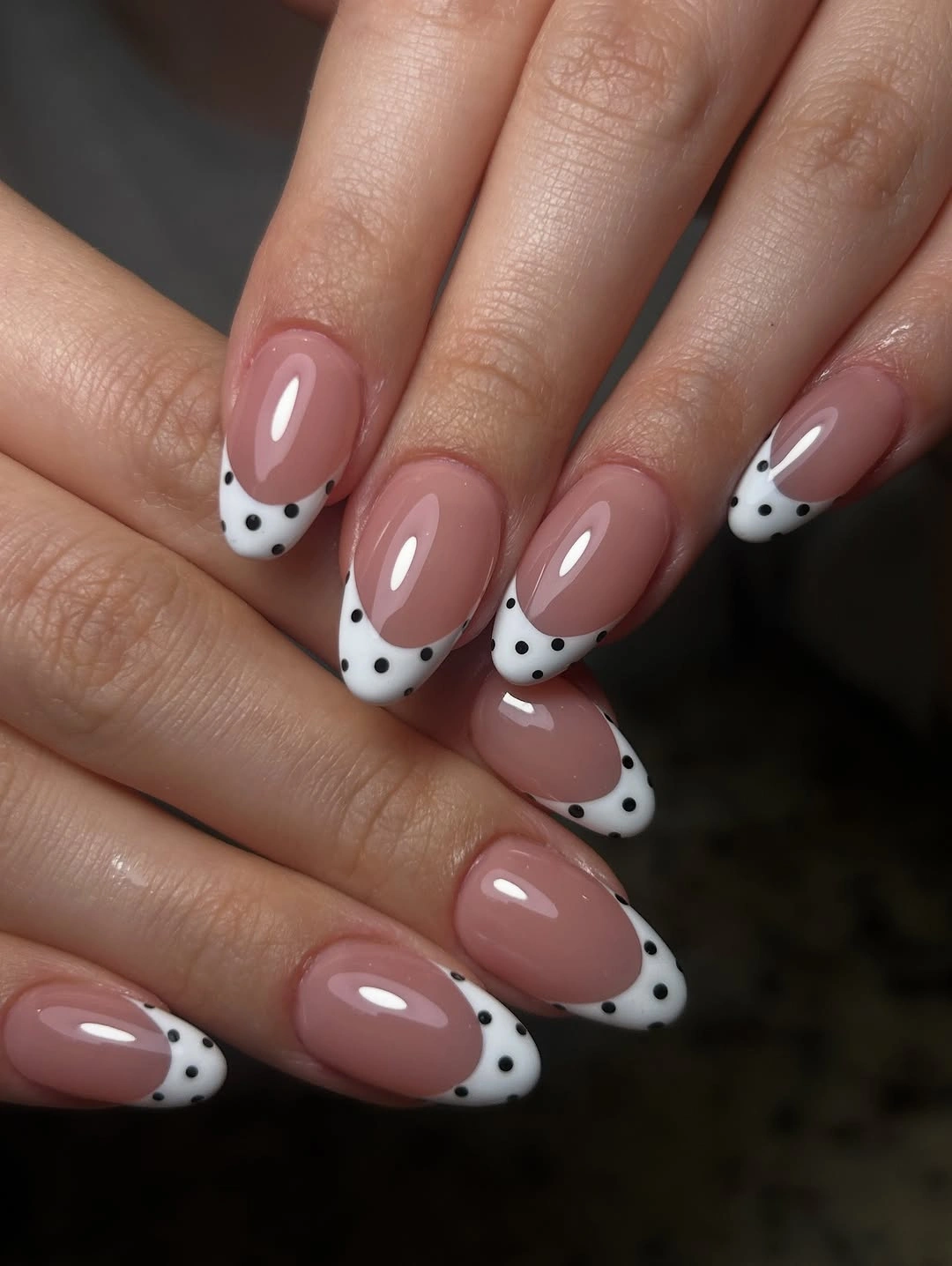 Medium nude almond nails with white French tips spotted in black cow print