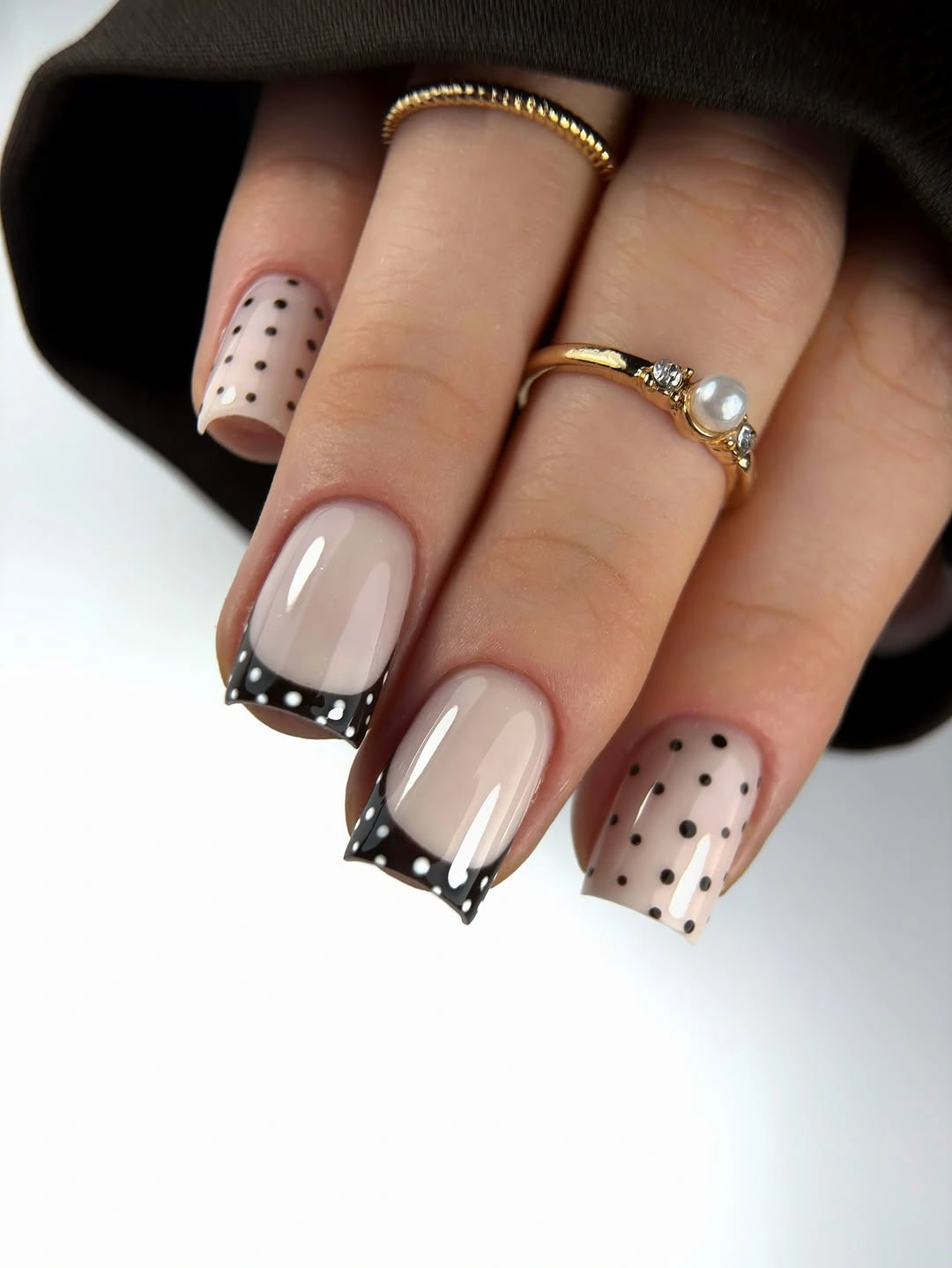 Long nude nails with varied black dotted tips thin outlines and pale dotted accent