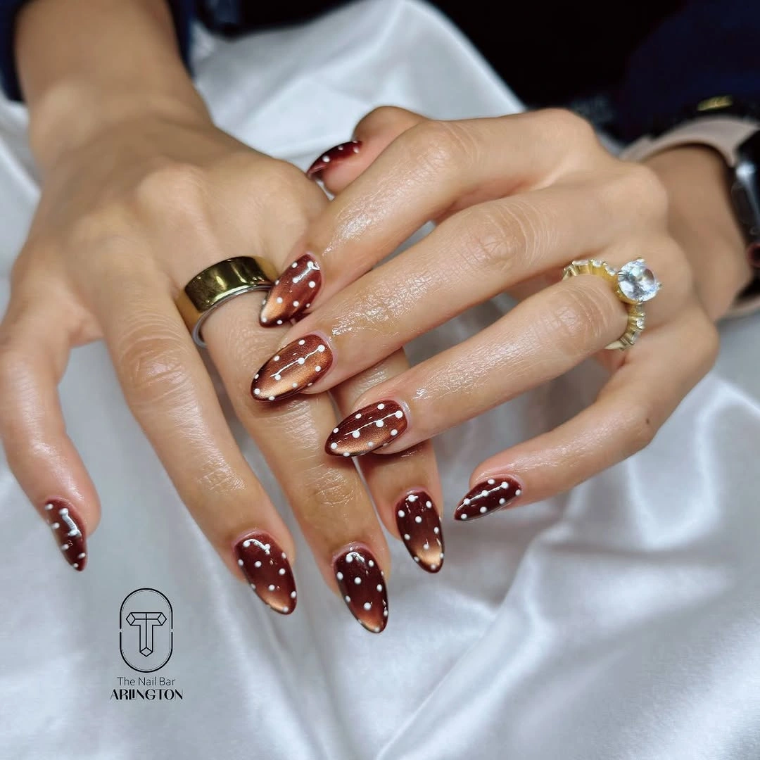 Long burgundy and cream almond nails with white dots and fine line accents