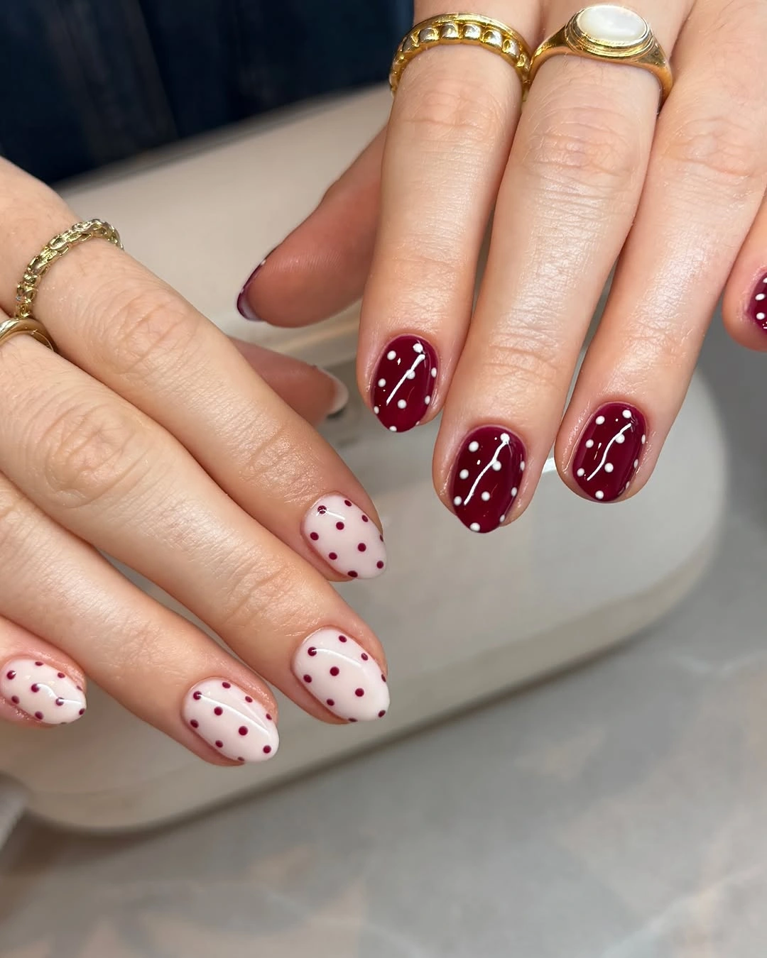 Short rounded burgundy and ivory nails with reversed tiny polka dots