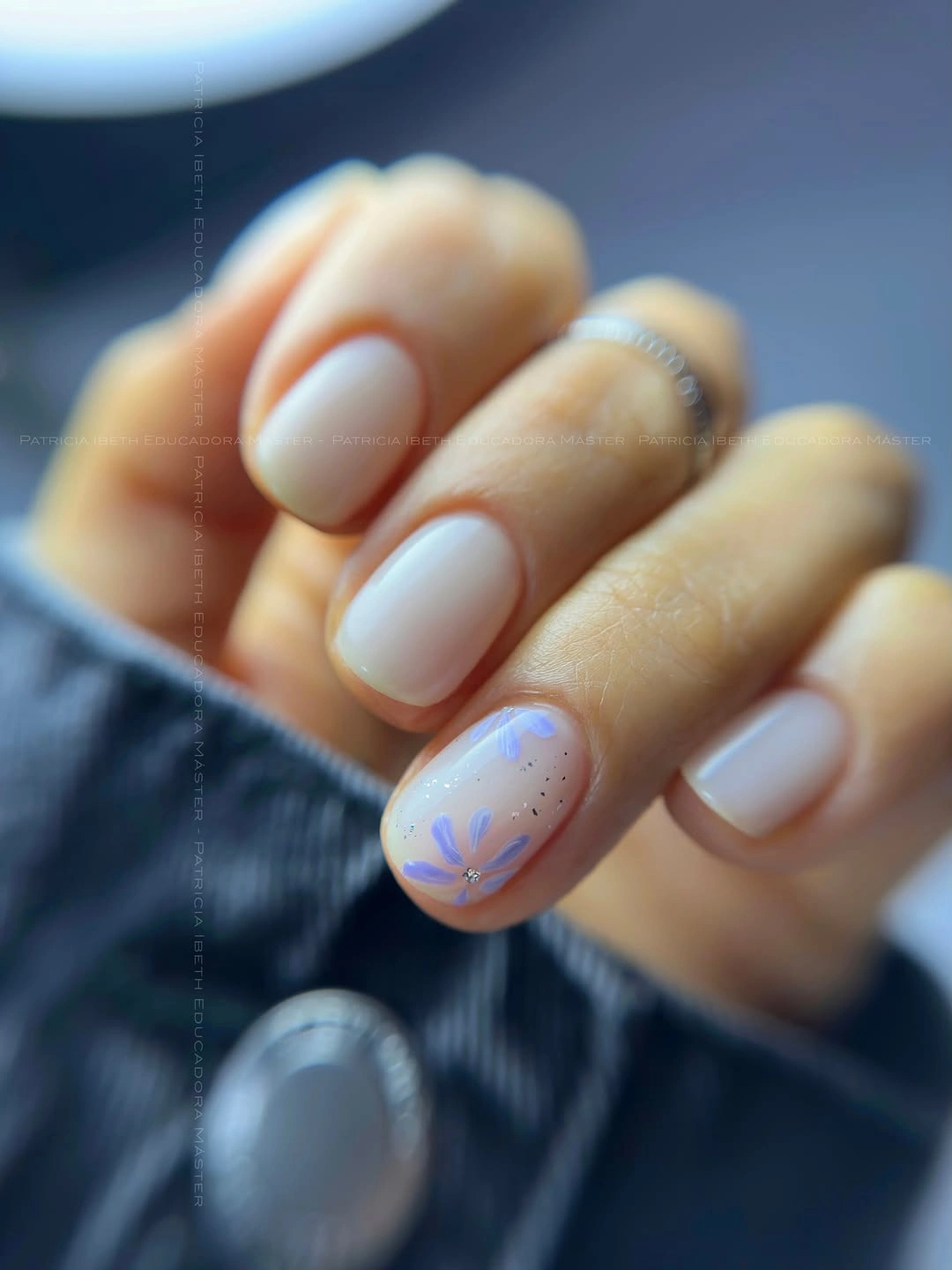 Milky short nails with blue floral accent
