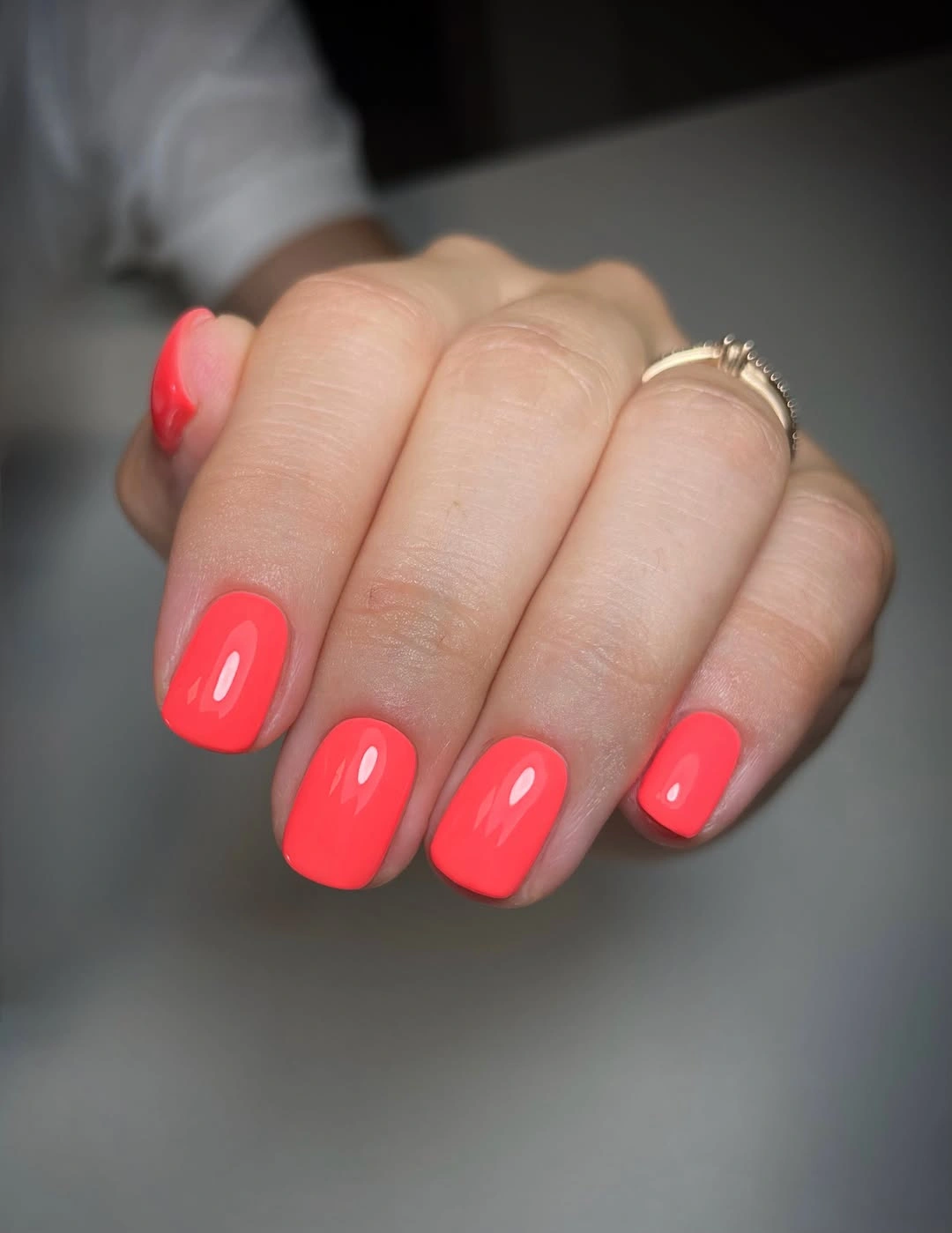 Short rounded-square nails with bright coral pink polish
