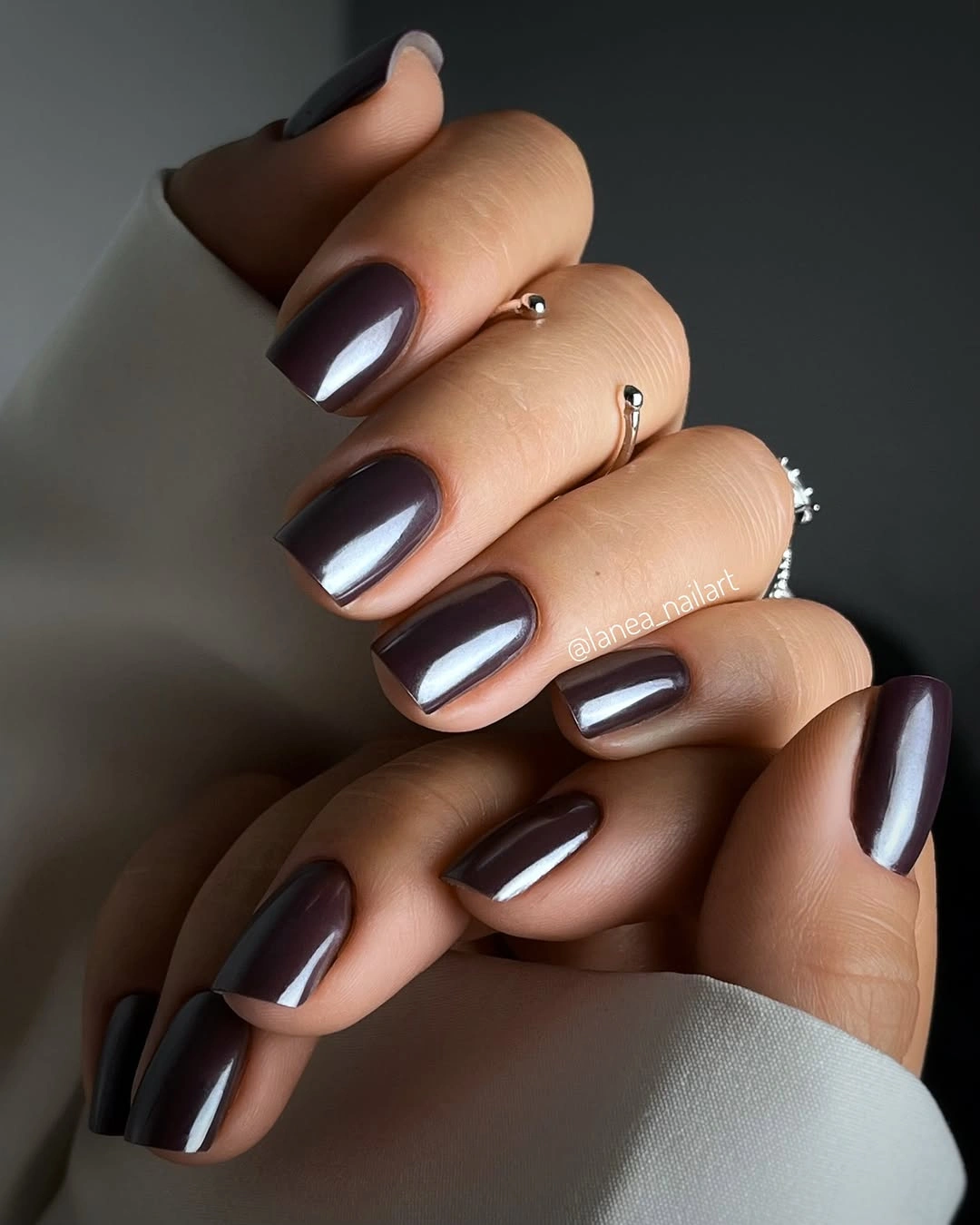 Short-to-medium almond-leaning nails with glossy dark chocolate-brown polish