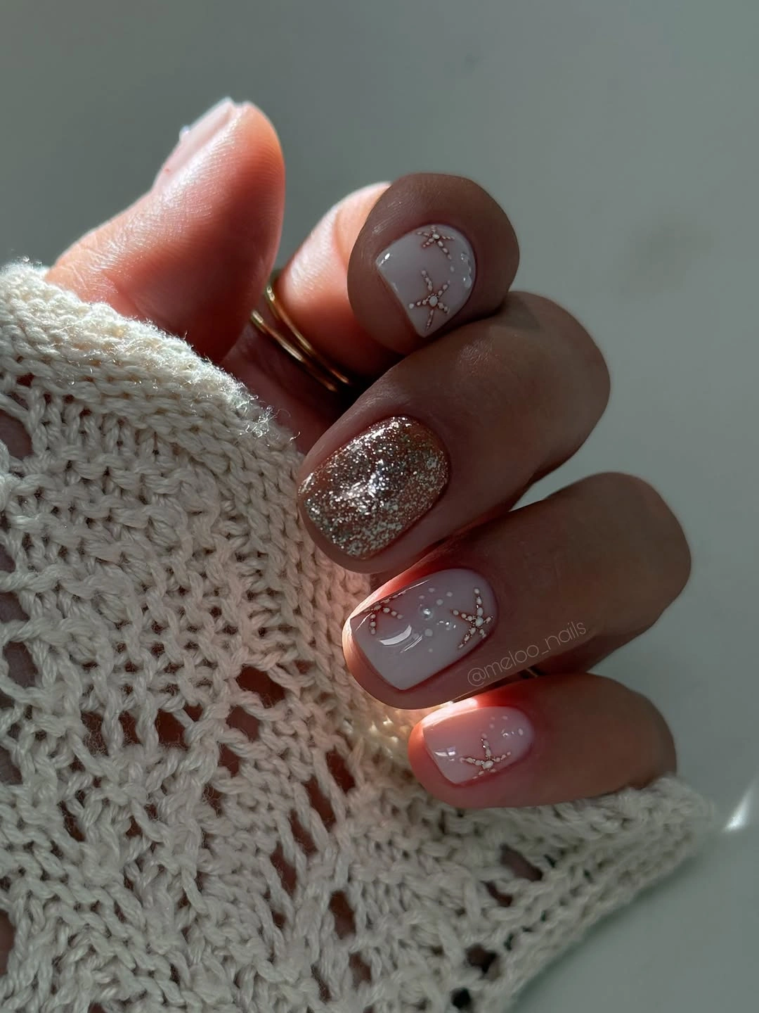 Short pale pink nails with glitter and gold dotted lines