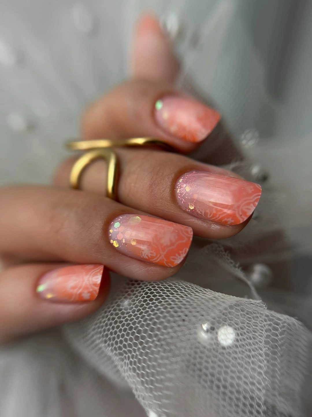 Peach coral nails with white swirls and shimmer